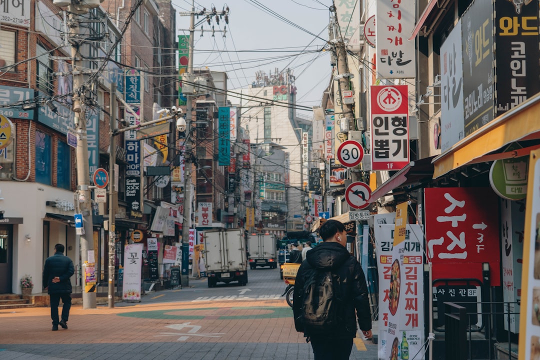 한국 대학교 캠퍼스에서 밝게 웃으며 노트북을 사용하는 유학생의 모습