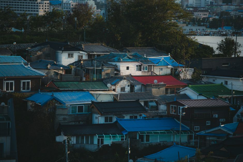 활기찬 한국의 소도시 또는 농촌 풍경. 현대적인 건물들이 자연과 어우러져 지역 개발과 공동체를 강조하며, 외국인들이 현지인들과 긍정적으로 교류하는 모습.